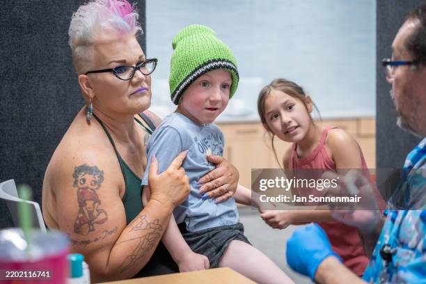 Ambra Hawksley holds her son Andrik Hawksley, age 6, while his sister JaeLynn holds his hand as he prepares to get an MMR vaccine from Raynard...