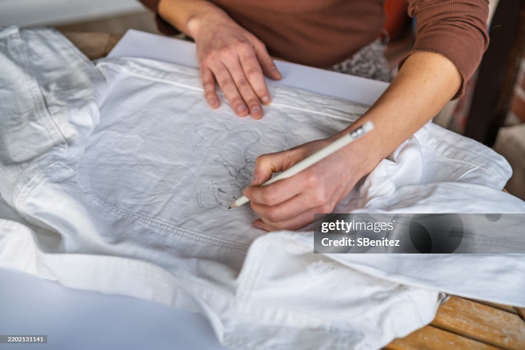 Fashion designer drawing sketches on a white shirt with a pencil