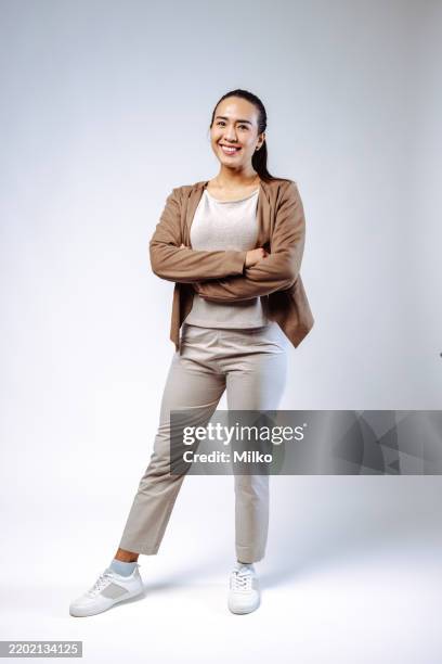 donna fiduciosa in abbigliamento professionale casual in posa con le braccia conserte su sfondo bianco - figura intera foto e immagini stock