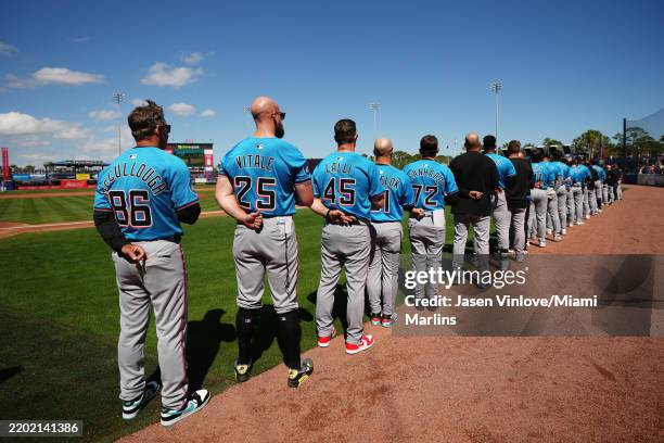 Clayton McCullough manager of the Miami Marlins and his team stand for the National Anthem prior to the spring training game against the New York...