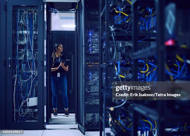female technician standing in server room - centre de traitement de données photos et images de collection