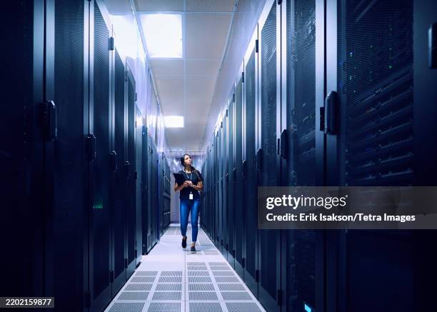 female technician walking in server room - centre de traitement de données photos et images de collection