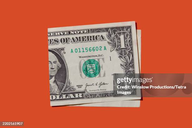 folded one dollar bill on orange background - banconota da 1 dollaro statunitense foto e immagini stock