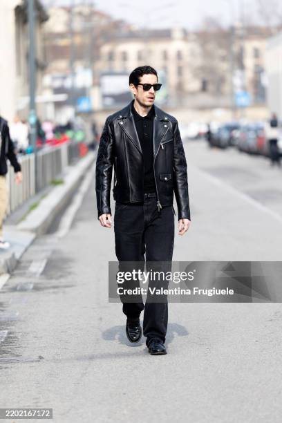 Guest wears black sunglasses, black denim trousers, black leather loafers, a black sweater and a black leather biker jacket outside Antonio Marras...