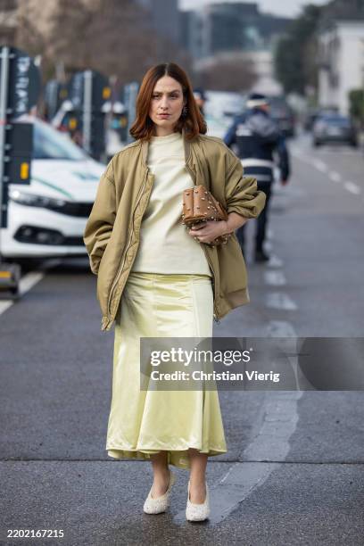 Erika Boldrin wears green bomber jacket, yellow skirt, shirt, brown bag outside Jil Sander during the Milan Fashion Week Womenswear Fall/Winter...