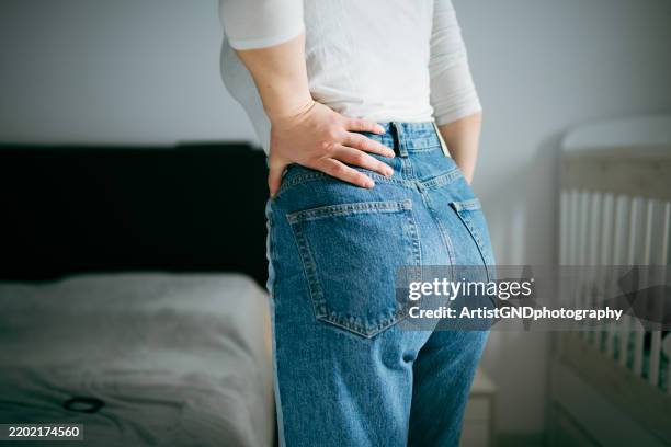 unrecognizable woman has severe lower back pain. - lower back stock pictures, royalty-free photos & images