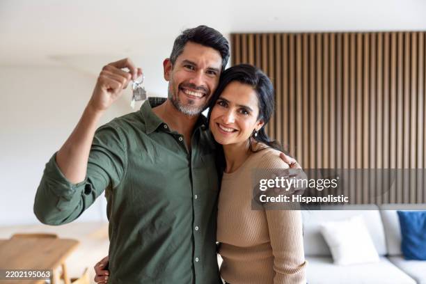 loving couple smiling while holding the keys of their new house - chave imagens e fotografias de stock