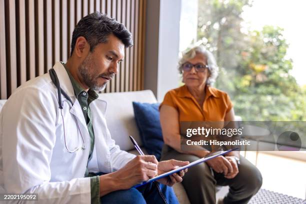 doctor examining a senior woman at home - form filling stock pictures, royalty-free photos & images