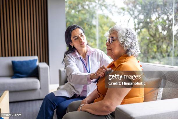 médecin effectuant un examen médical sur une femme âgée à domicile - auscultation au stéthoscope photos et images de collection