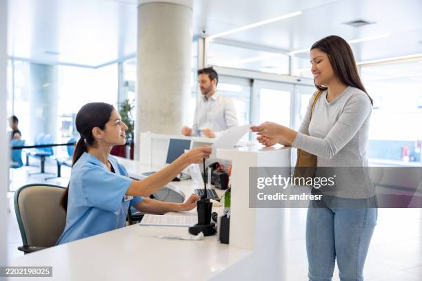 patient at the hospital handing a form to a nurse at the reception - reception bildbanksfoton och bilder