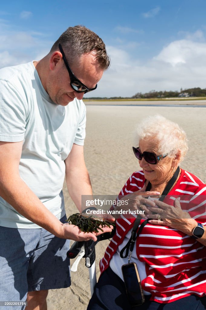 Man shows his mother a hermit crab on Skaket Beach