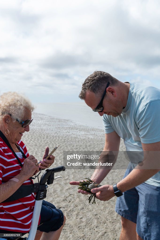 Man shows his mother a hermit crab on Skaket Beach