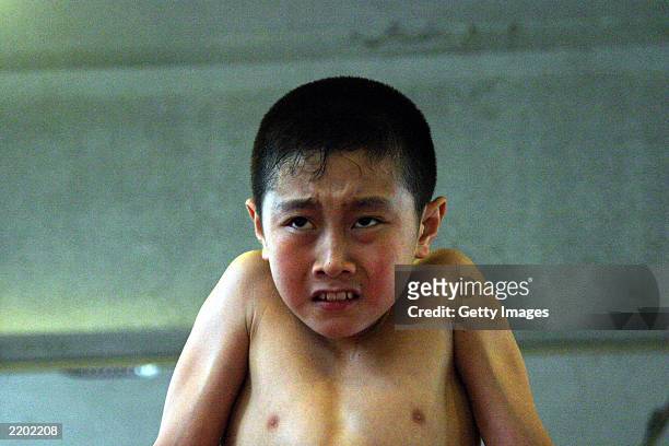 Young boy appears to struggle as he tries to keep himself on the parallel bars at the state owned Shichahai sports school July 25, 2003 in Beijing,...
