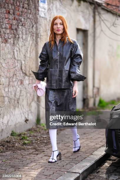 Guest wears shiny black textured oversized leather jacket, silver necklace, shiny silver textured midi skirt, white tights, black open toe heels,...