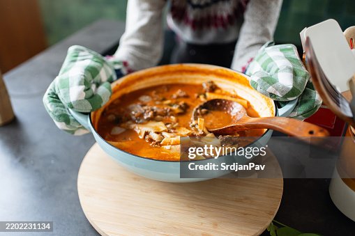Person presenting a hearty bowl of warm soup in a cozy kitchen Person presenting a hearty bowl of warm soup in a cozy kitchen