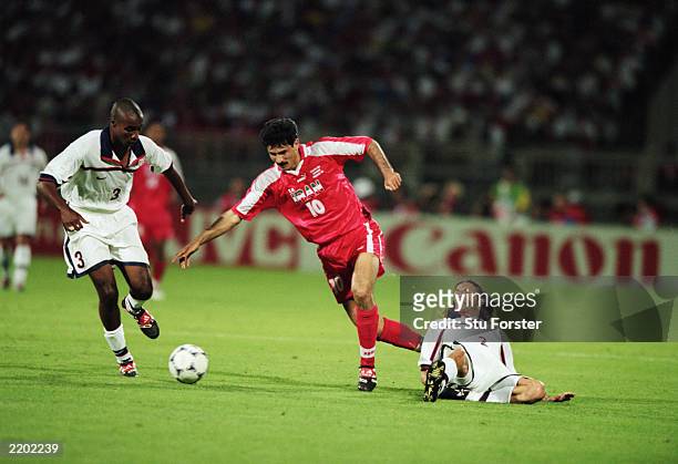 Ali Daei of Iran takes the ball past Eddie Pope and Frankie Hejduk of the USA during the FIFA World Cup Finals 1998 Group F match between the USA and...