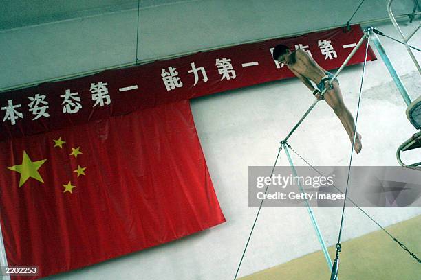 Student starts exercising on the horizontal bar during the daily training at the state owned Shichahai sports school July 25, 2003 in Beijing, China....