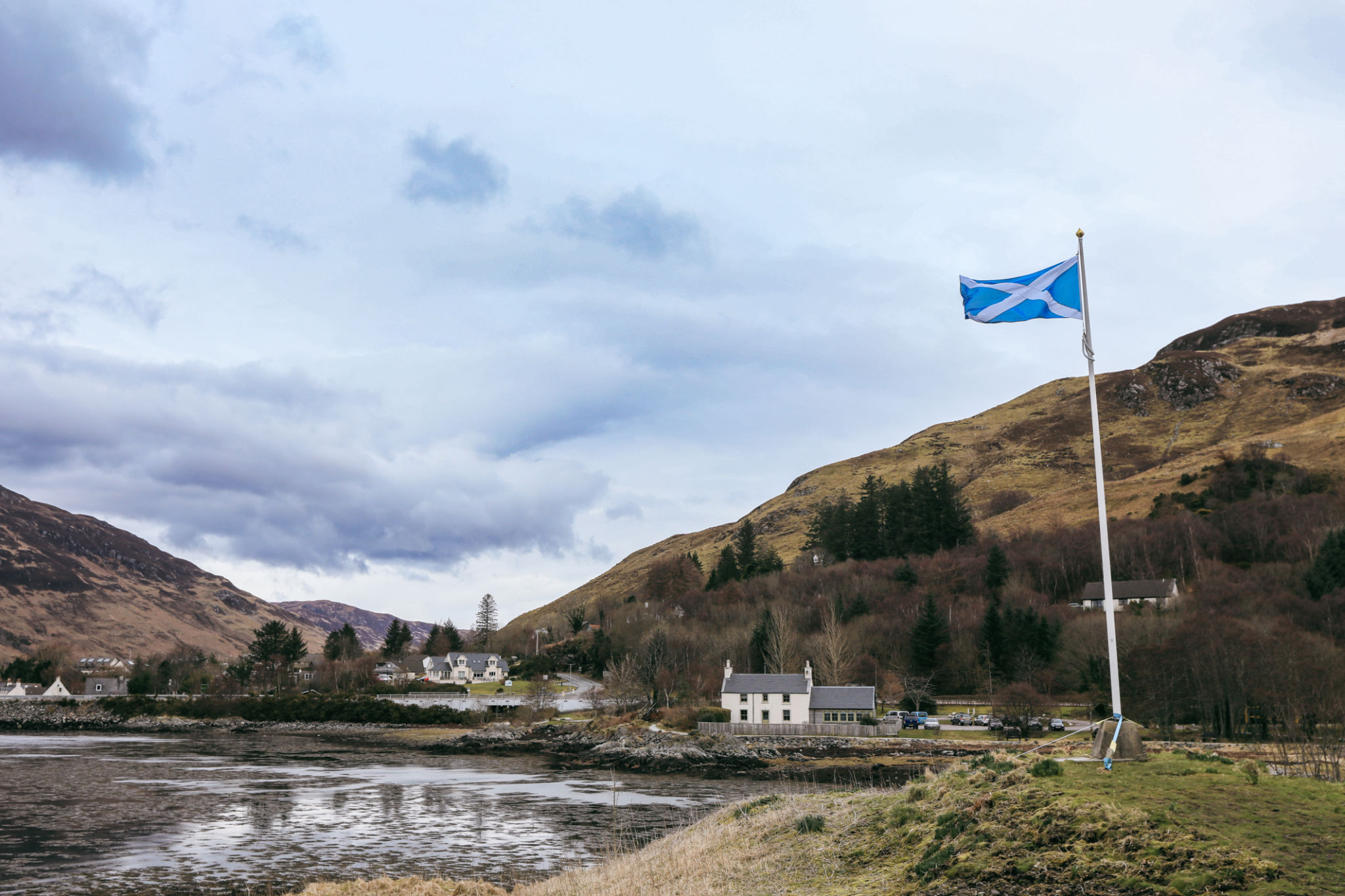 Scenic Scotland countryside with a flag waving by mountains and homes Scenic Scotland countryside with a flag waving by mountains and homes