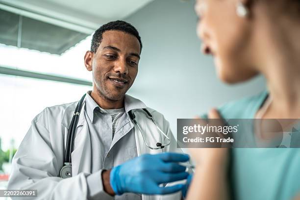 doctor vaccinating a young woman - immunology stock pictures, royalty-free photos & images