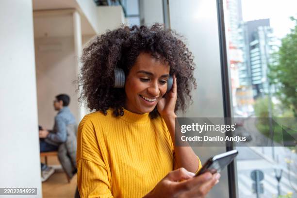 woman using her smartphone in a caffe - woman caffe stockfoto's en -beelden