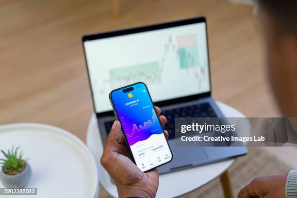 trader analyzing cryptocurrency market data on smartphone and laptop - digital currency stock pictures, royalty-free photos & images