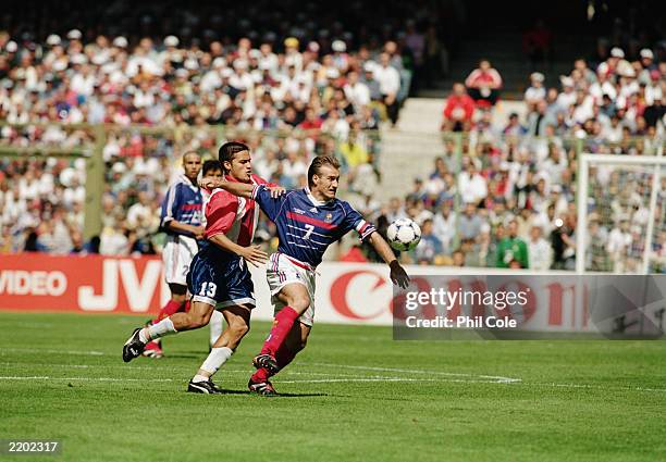 Didier Deschamps of France is held back by Carlos Paredes of Paraguay during the FIFA World Cup Finals 1998 Second Round match between France and...