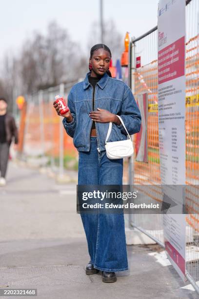 Guest wears burgundy bordeaux earring, black high neck cropped long sleeve shirt, dark blue denim jean bomber Diesel bomber jacket, dark blue denim...