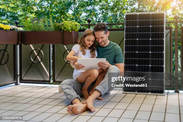 daughter using tablet pc with father sitting next to solar panel in balcony - portability stock pictures, royalty-free photos & images
