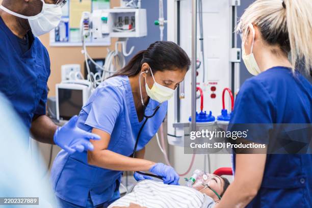 notaufnahme des krankenhauses: vielfältiges medizinisches team, das sich um den patienten kümmert - notfallmedizin stock-fotos und bilder