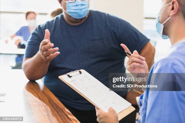 el médico y el paciente discuten sobre la historia clínica durante una consulta - obesidad fotografías e imágenes de stock