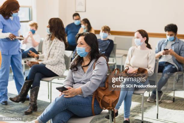 un grupo diverso de personas que esperan pacientemente en el consultorio de un médico - pandemia fotografías e imágenes de stock
