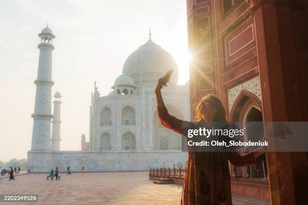 woman photographing with smartphone near taj mahal in india - agra fotografías e imágenes de stock