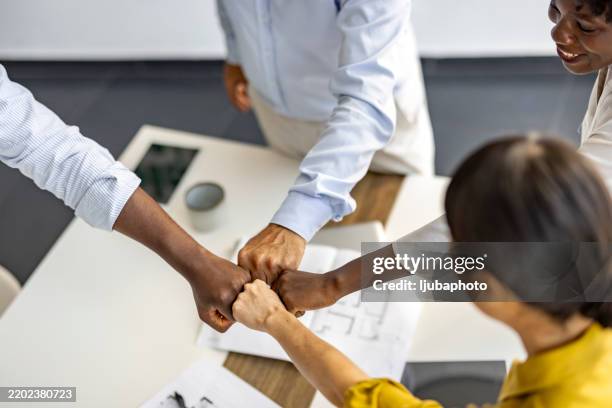 diverse team celebrating success with fist bump in office - fist bump stock pictures, royalty-free photos & images