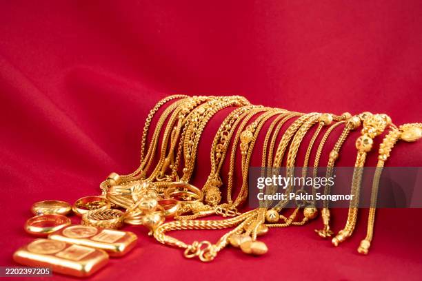 group of gold necklaces, rings and gold bars on red silk background. - gold medal stock pictures, royalty-free photos & images