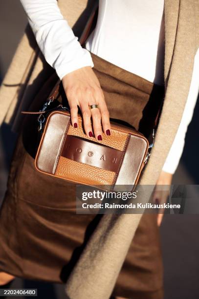 Guest wears brown skirt, white long sleeve top, beige scarf, and brown bag outside Hogan event during the Milan Fashion Week Womenswear Fall/Winter...