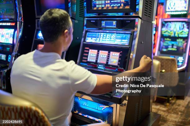 man playing slot machine - jugar a juegos de azar fotografías e imágenes de stock
