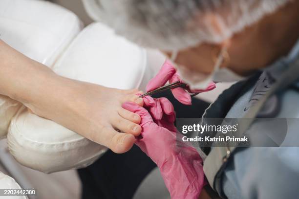a professional pedicure specialist carefully treating a client's feet using a special device, ideal for beauty, self-care, and wellness-related content - pedicure stock pictures, royalty-free photos & images