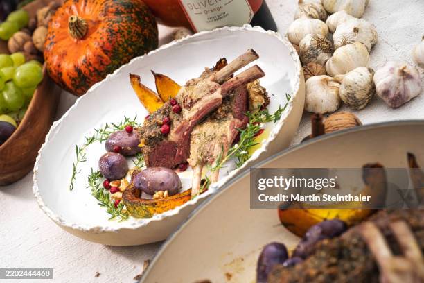 roast lamb with bones, assorted vegetables, pumpkin and blue potatoes. - lammkeule stock-fotos und bilder