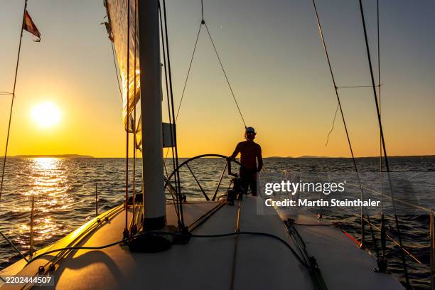 skipper with hands on the rudder of a sailing ship close to sunset on a soft windy day at the sea. - timón fotografías e imágenes de stock