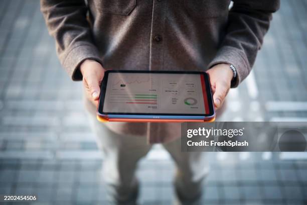 businessperson holding a tablet displaying analytics data and performance charts - financial report stock pictures, royalty-free photos & images