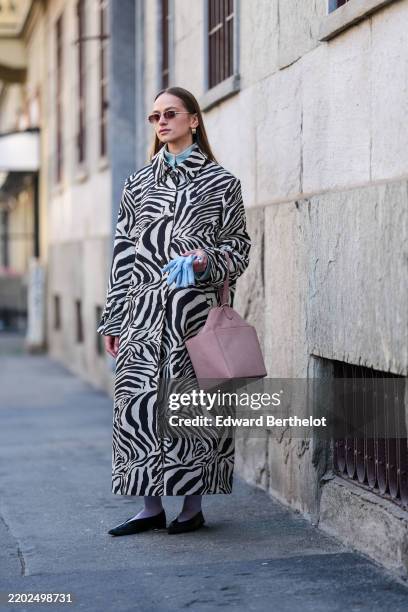 Guest wears dark brown sunglasses, gold earrings, light blue buttoned up long sleeve shirt, white black zebra pattern/print coat, light blue gloves,...