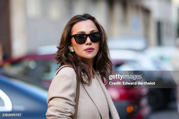 Yasemin Ogun wears black Ray Ban sunglasses, silver earrings, light brown oversized wool blazer jacket, outside Max Mara, during the Milan Fashion...