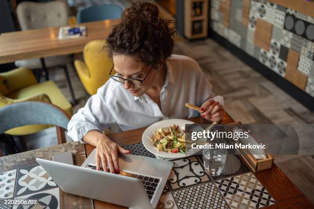 freiberufler, der am laptop arbeitet und salat im restaurant isst - mittag stock-fotos und bilder