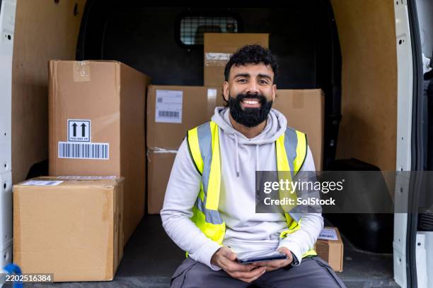 joyful delivery guy sitting in van - reflective clothing stock pictures, royalty-free photos & images