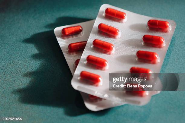 medicine and healthcare. two blister packs with red iron capsules against blue background - blister pack stock pictures, royalty-free photos & images