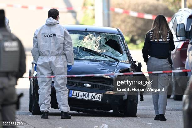 Police stand next to a damaged car, possibly the car used by the assailant who drove a car into pedestrians on March 3, 2025 in Mannheim, Germany....