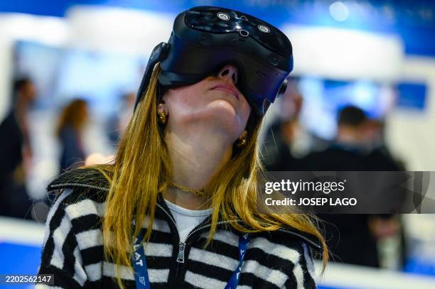 An attendee tries out an HTC VIVE virtual reality headset during the MWC , the world's biggest mobile fair, in Barcelona on March 3, 2025. Surrounded...