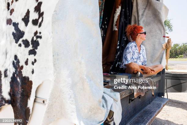 entrepreneurial spirit amid cowhides. vibrant texan businesswoman showcases artisanal leather goods. - pop up store stock pictures, royalty-free photos & images
