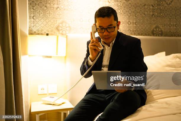 uomo d'affari in camera d'albergo che ordina il servizio in camera - servizio in camera foto e immagini stock