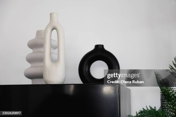 modern vases on a black box near a green plant by a metallic textured cylinder. - réfrigérateur fermé photos et images de collection